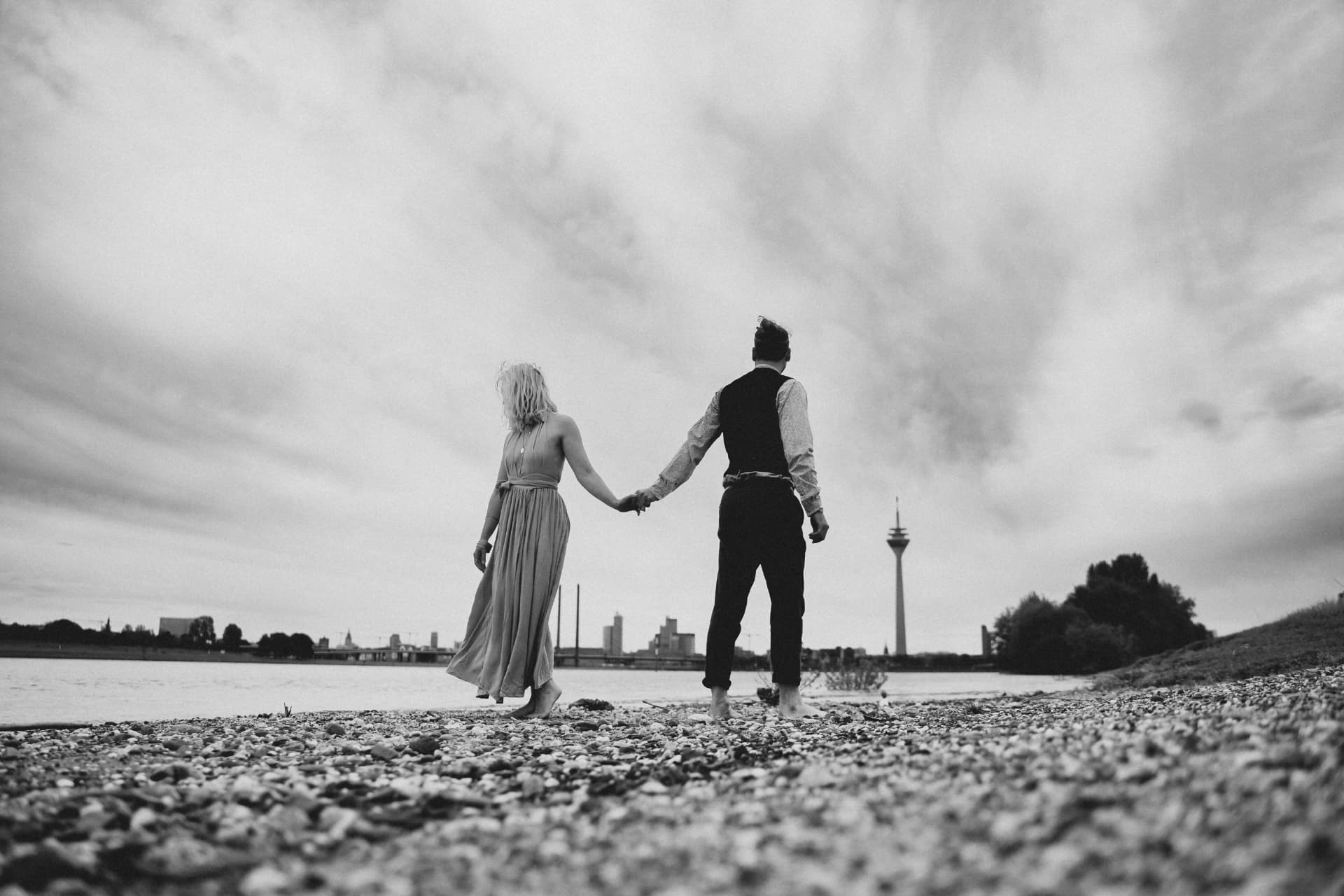 Brautpaar Hand in Hand am Rheinufer mit Düsseldorfer Skyline in Schwarzweiß